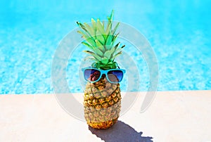 Fashion pineapple with sunglasses on a blue water pool