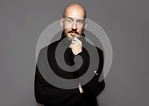 Fashion Portrait of a 40-year-old man standing over a light gray background in a black sweater. Close up. Classic style. Bald