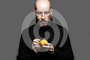 Fashion Portrait of a 40-year-old man standing over a light gray background in a black sweater. Close up. Classic style. Bald