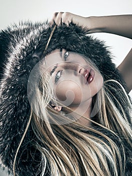 Fashion portrait of attractive blonde woman in fur coat hood