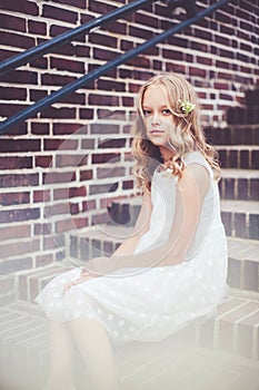 Fashion portrait of beautiful 9 -10 years old girl sitting on the stairs.