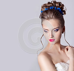 Fashion portrait of a beautiful attractive girl with a gentle elegant evening wedding hairstyles high and bright make-up with flow