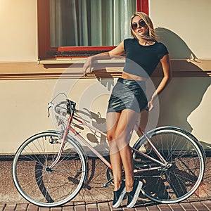 Fashion portrait of beautiful blonde girl near vintage bicycle