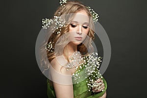 Fashion portrait of beautiful blonde woman with flowers on black background