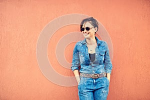 Fashion portrait with beautiful funny woman on terrace wearing modern jeans outfit, sunglasses and smiling. Instagram filter