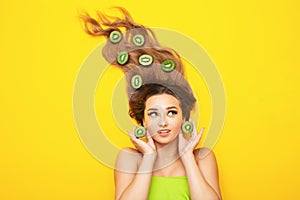 Fashion portrait of beautiful girl on colored background with kiwi slices on long hair, young woman head, fruit energy,tropical