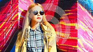 Fashion portrait of beautiful stylish blonde young woman on city street over colorful graffiti background