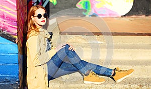 Fashion portrait of beautiful stylish blonde young woman on city street over colorful graffiti background