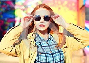 Fashion portrait of beautiful stylish blonde young woman on city street over colorful graffiti background