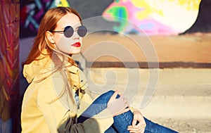 Fashion portrait of beautiful stylish blonde young woman on city street over colorful graffiti background