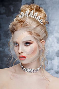 Fashion Portrait of Beautiful Woman with Tiara on head. Elegant Hairstyle. Perfect Make-Up and Jewelry. Coral Lips