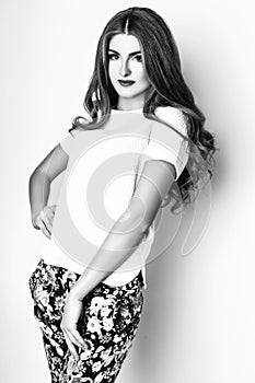 Fashion portrait of beautiful young woman with long hair. Girl in a white blouse and pants on a white background. Black and white