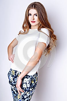 Fashion portrait of beautiful young woman with long hair. Girl in a white blouse and pants on a white background