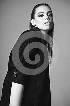 Fashion portrait of a beautiful young woman posing in a black evening suit