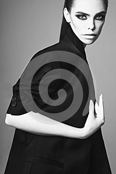 Fashion portrait of a beautiful young woman posing in a black evening suit