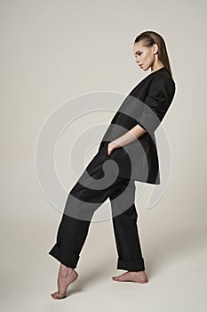 Fashion portrait of a beautiful young woman posing in a black evening suit