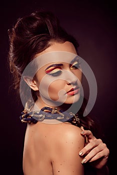 Fashion portrait of brown-eyes woman. Gold jewelry. Orange yell