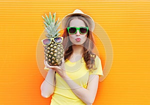 Fashion portrait cool girl in sunglasses with pineapple over colorful orange