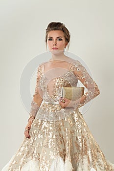 Fashion portrait of elegant luxurious woman in trendy gold sequin party dress holding trendy evening purse. Elegant hairdo, makeup