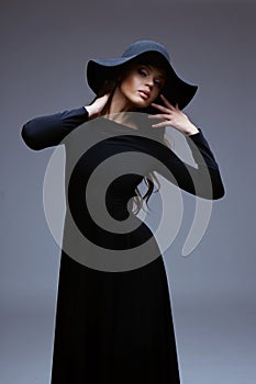 Fashion portrait of elegant woman in black hat and dress