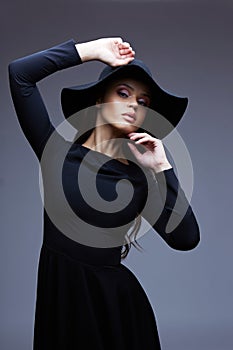 Fashion portrait of elegant woman in black hat and dress