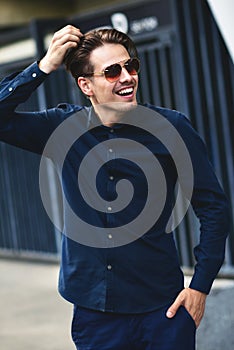 Fashion portrait of european guy in sunglasses walking on streets at city