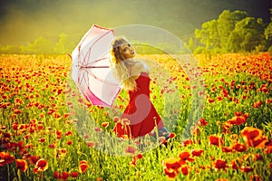 Fashion portrait of a girl with an umbrella. woman in field of poppy seed with umbrella