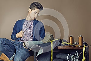 Fashion portrait of handsome young man with tools for sewing den photo