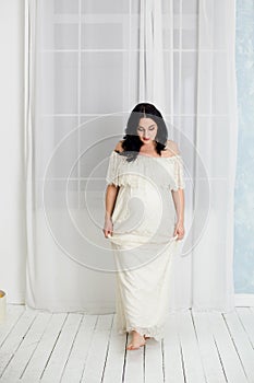 Fashion portrait of happy pregnant woman in white dress