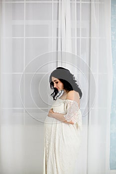 Fashion portrait of happy pregnant woman in white dress