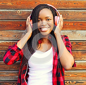 Fashion portrait happy smiling african woman with a headphones is enjoying listens to music