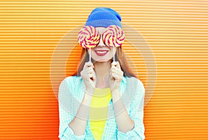 Fashion portrait happy smiling woman and lollipop is having fun over colorful orange