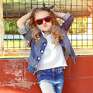 Fashion portrait little girl child in jeans jacket, red sunglasses posing