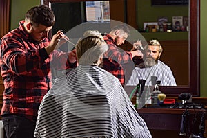 Fashion portrait of man. Barbershop. Young hipster man with beard cutting his hair in a barbershop. Professional