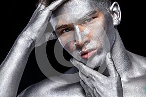 A fashion portrait of man with silver bodyart and face art.