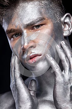 A fashion portrait of man with silver bodyart and face art.