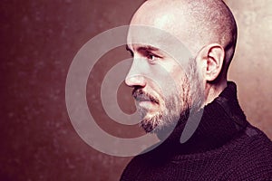 Fashion Portrait man standing over a light golden background in a black sweater. Close up. Classic style. Bald shaved head. Copy-