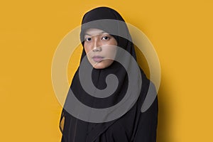 Fashion portrait model of young beautiful muslim woman wearing hijab isolated on yellow background