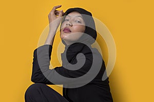 Fashion portrait model of young beautiful muslim woman wearing hijab isolated on yellow background