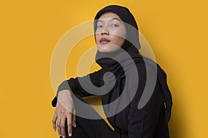 Fashion portrait model of young beautiful muslim woman wearing hijab isolated on yellow background