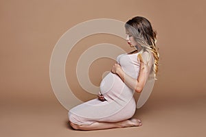 Fashion portrait pregnant woman blonde, perfect figure of girl. Woman is waiting for birth of a baby. Art woman in late pregnancy
