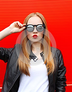 Fashion portrait pretty blonde woman with red lipstick wearing a rock black style and sunglasses having fun