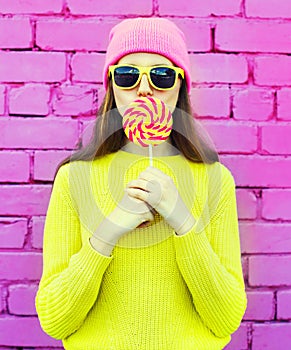 Fashion portrait pretty cool girl having fun with lollipop over pink