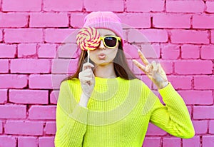 Fashion portrait pretty cool girl with lollipop having fun over colorful pink