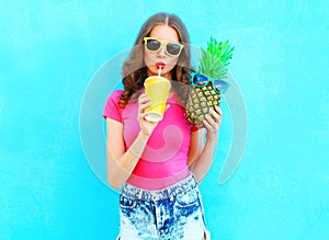 Fashion portrait pretty cool girl and pineapple drinking juice from cup over colorful