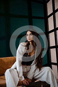 Fashion portrait of pretty sexy young brunette woman in white pantsuit