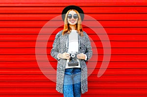 Fashion portrait pretty smiling woman holds retro camera on a red