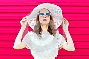 Fashion portrait pretty woman in white summer straw hat over colorful pink