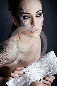 Fashion portrait of pretty young woman with creative make up like a snake