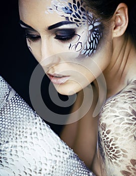 Fashion portrait of pretty young woman with creative make up like a snake, fashion victim with python skin clutch